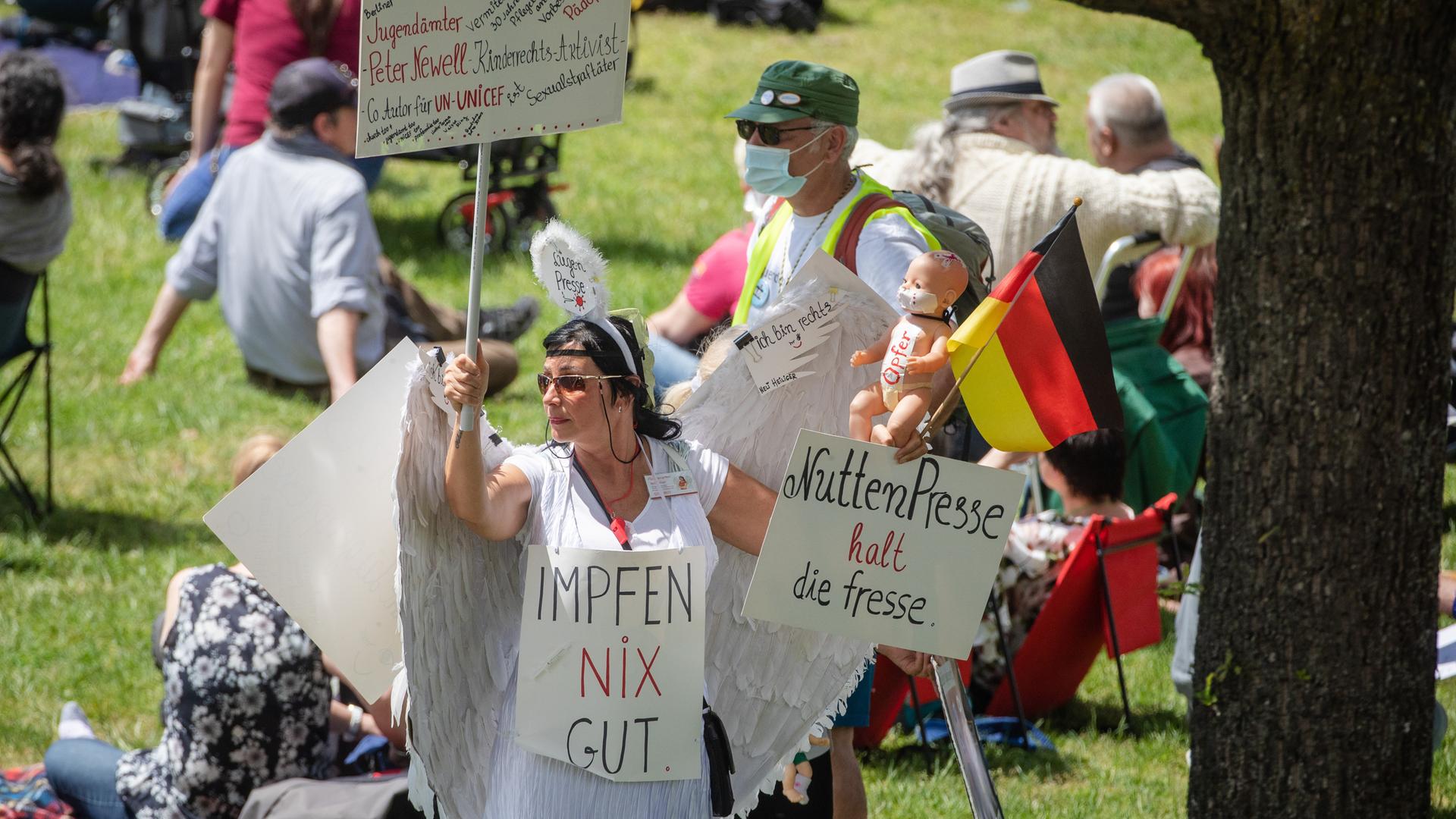 Eine Frau hält auf einer "Querdenker"-Demonstration Schilder, auf denen " Impfen nix gut" und "NuttenPresse halt die Fresse" steht. Eine Frau hält auf einer "Querdenker"-Demonstration Schilder, auf denen " Impfen nix gut" und "NuttenPresse halt die Fresse" steht.