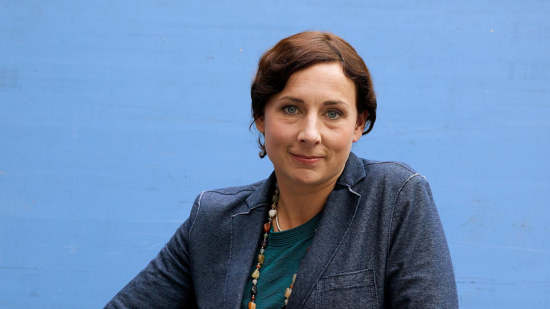 Juli Zeh in blauer Jacke lächelt in die Kamera. Juli Zeh in blauer Jacke lächelt in die Kamera.
