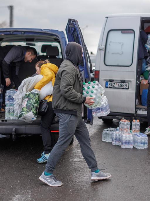 Freiwillige verteilen Wasser an Ukrainische Geflüchtete nach dem Grenzübertritt in Polen. 