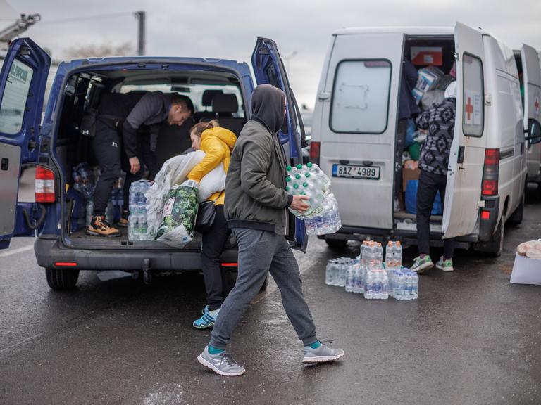 Freiwillige verteilen Wasser an Ukrainische Geflüchtete nach dem Grenzübertritt in Polen. 