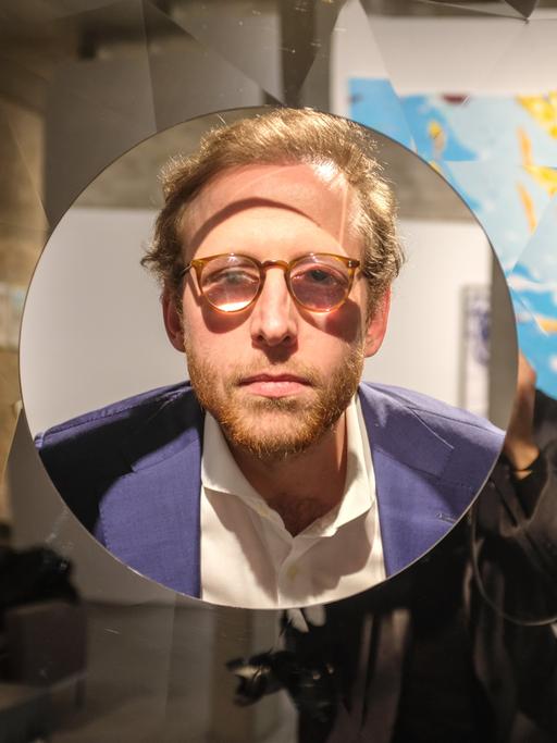 Johann König schaut schaut durch ein Fenster seiner Galerie in Berlin