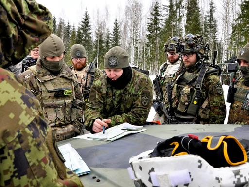 Militärs beugen sich beim NATO-Manöver in Estland im Februar 2022 über Kartenmaterial auf einem Panzer