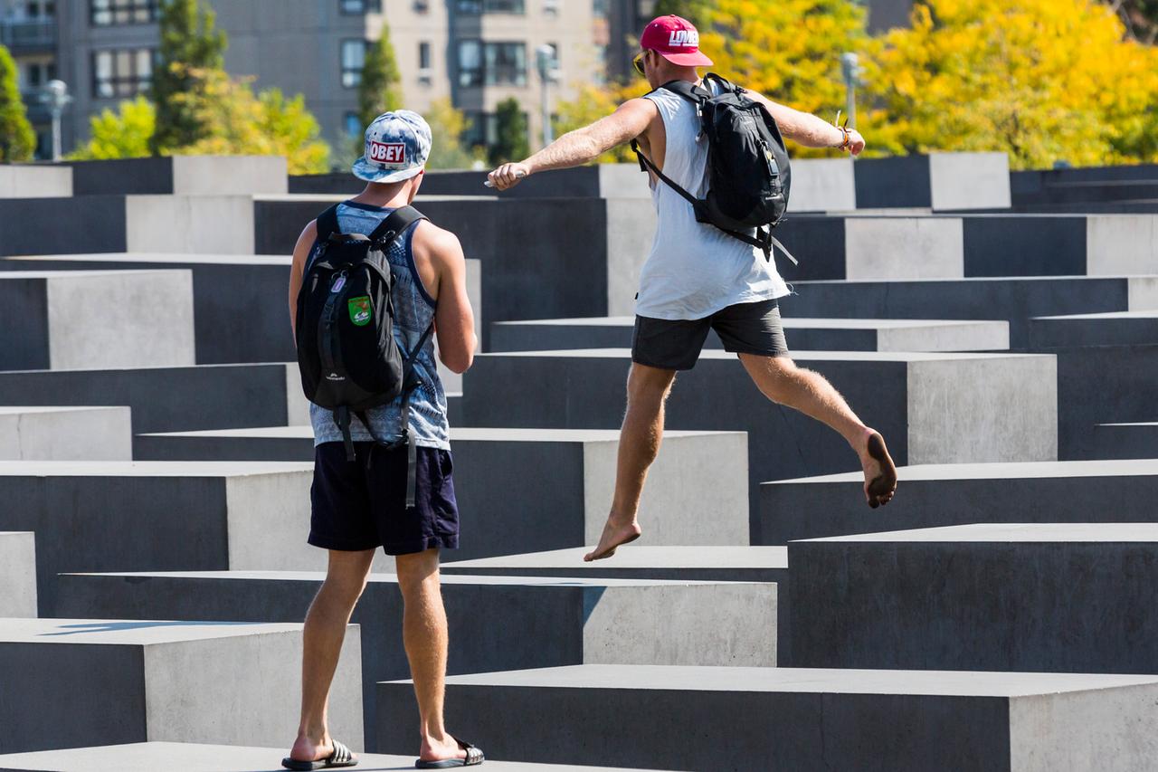Touristen springen auf den Stelen des Holocaust-Mahnmal in Berlin. Touristen springen auf den Stelen des Holocaust-Mahnmal in Berlin.