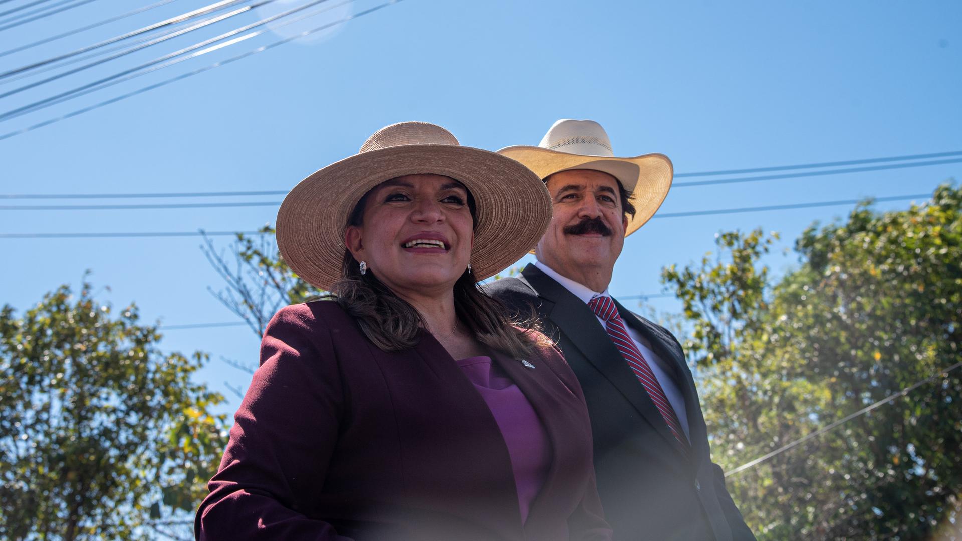 Die gewählte Präsidentin Xiomara Castro und ihr Ehemann, der ehemalige Präsident Manuel Zelaya, lächeln ihren Anhängern während einer Veranstaltung zur Amtseinführung zu. Beide tragen große Sombreros. Die gewählte Präsidentin Xiomara Castro und ihr Ehemann, der ehemalige Präsident Manuel Zelaya, lächeln ihren Anhängern während einer Veranstaltung zur Amtseinführung zu. Beide tragen große Sombreros.