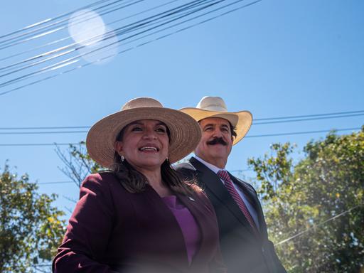 Die gewählte Präsidentin Xiomara Castro und ihr Ehemann, der ehemalige Präsident Manuel Zelaya, lächeln ihren Anhängern während einer Veranstaltung zur Amtseinführung zu. Beide tragen große Sombreros.