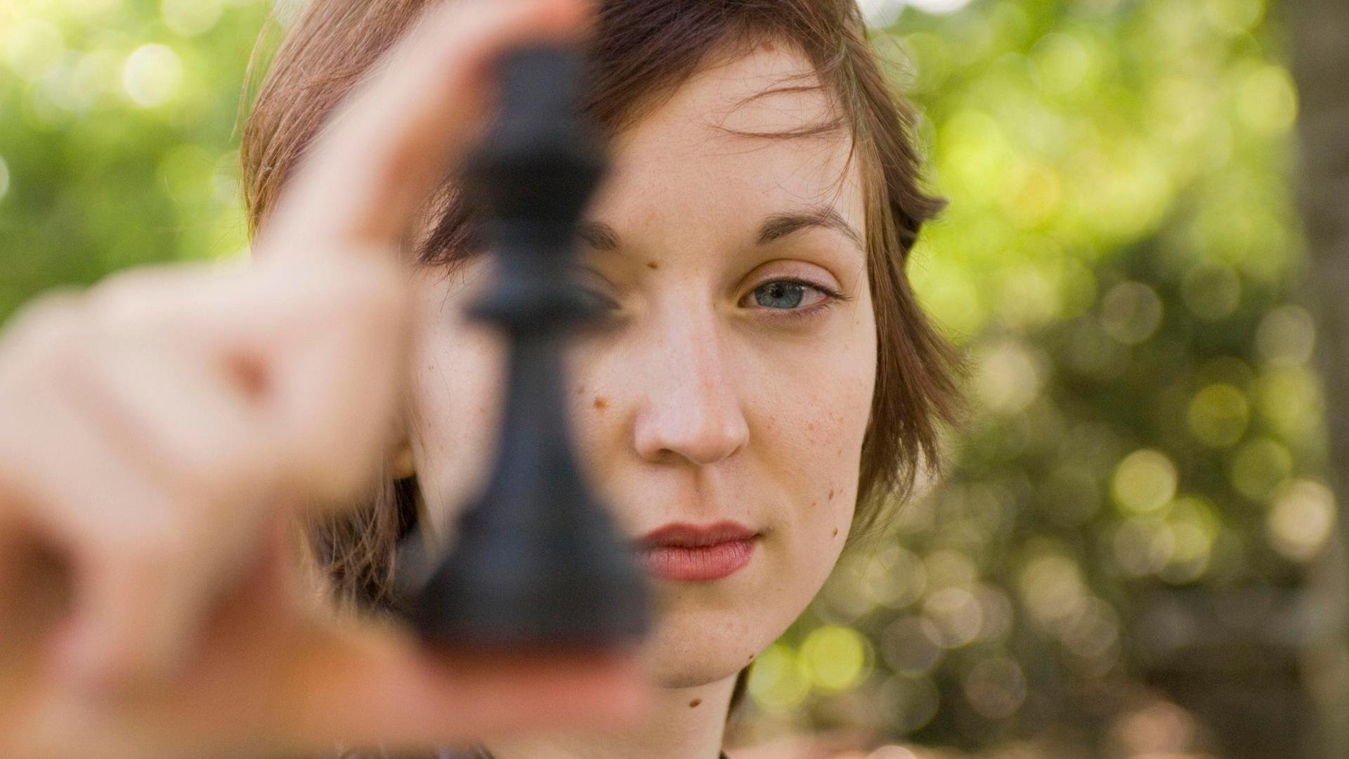 Porträt von Elisabeth Pähtz als Junioren-Weltmeisterin im Schach. Sie hält sich eine Schafigur vor das linke Auge und schaut dabei sehr ernst. Porträt von Elisabeth Pähtz als Junioren-Weltmeisterin im Schach. Sie hält sich eine Schafigur vor das linke Auge und schaut dabei sehr ernst.