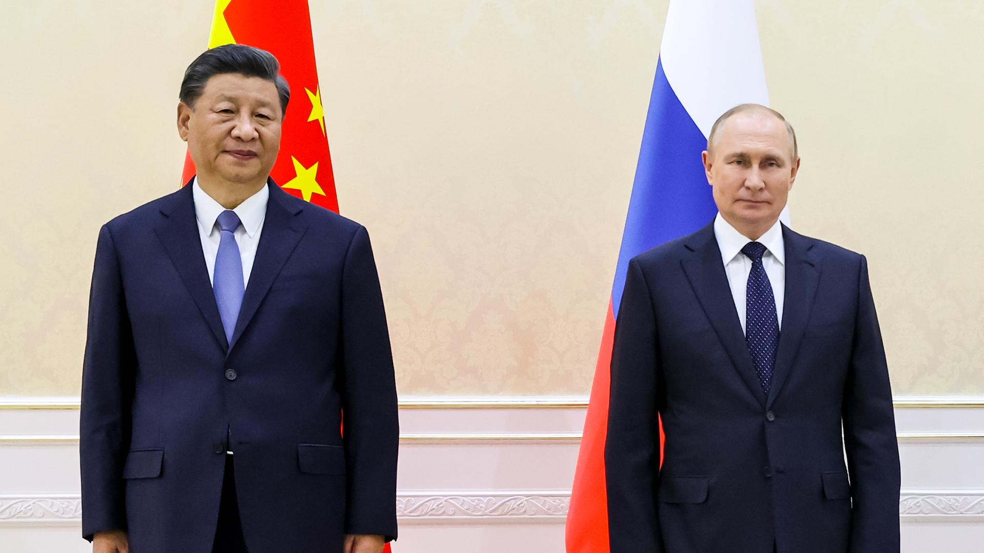 Der chinesische Präsident Xi Jingping und der russische Präsident Wladimir Putin stehen vor ihren jeweiligen Landesflaggen