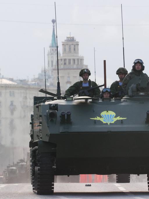 Vier russische Soldaten fahren mit einem Militärfahrzeug auf den Roten Platz in Moskau, um an der Siegesparade zum 9. Mai teilzunehmen. 
