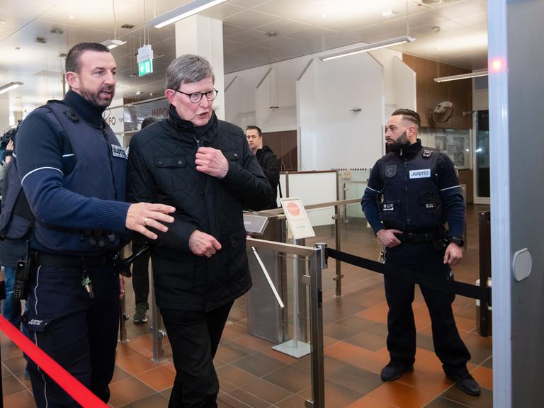 Köln: Kardinal Rainer Maria Woelki (2.v.l) wird im Foyer des Landgerichts von einem Justizbeamten zur Sicherheitsschleuse begleitet.