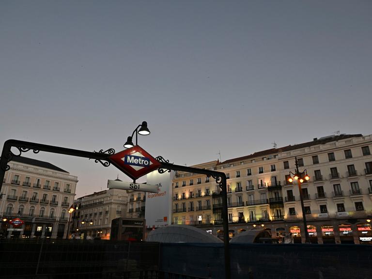 Eine Metro-Station in der Innen-Stadt von Madrid leuchtet schwach in der Dämmerung.