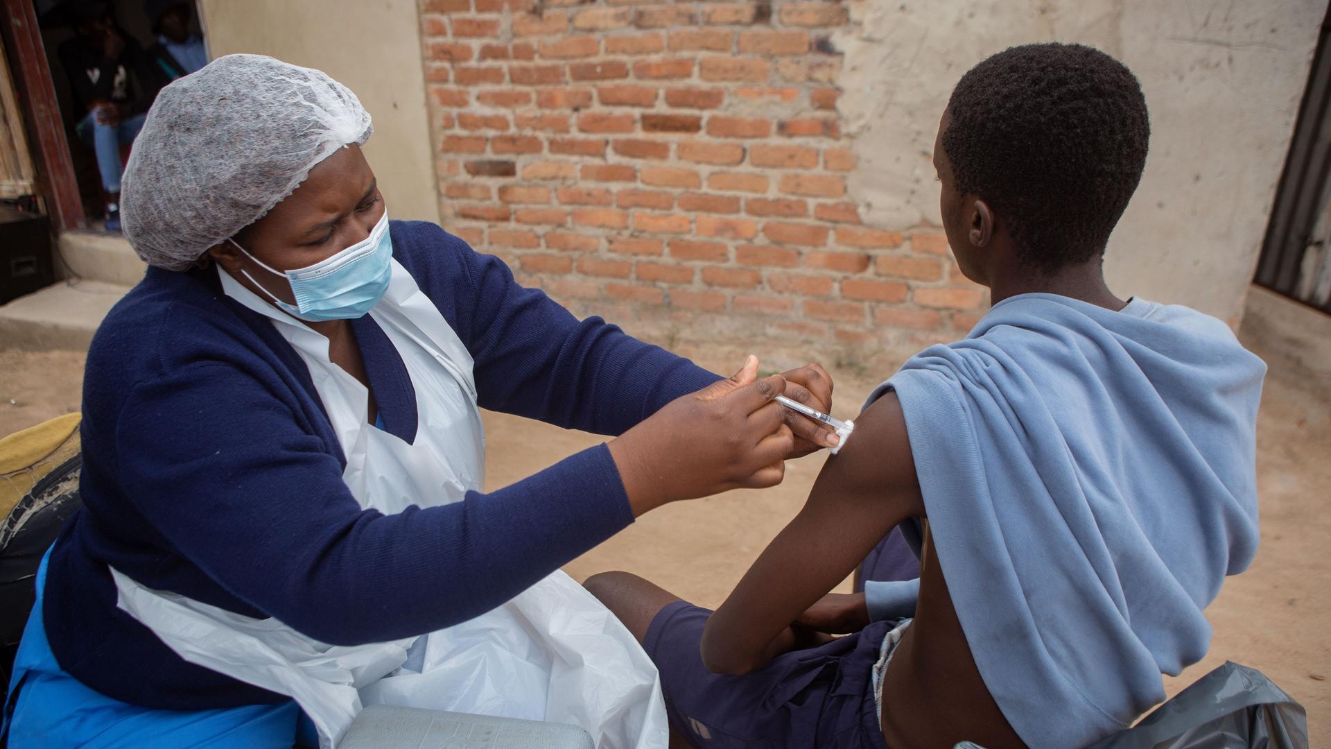 Eine mobile Impfstation in Harare, Simbabwe: Eine Krankenschwester impft einen jungen Mann gegen Corona. Eine mobile Impfstation in Harare, Simbabwe: Eine Krankenschwester impft einen jungen Mann gegen Corona.