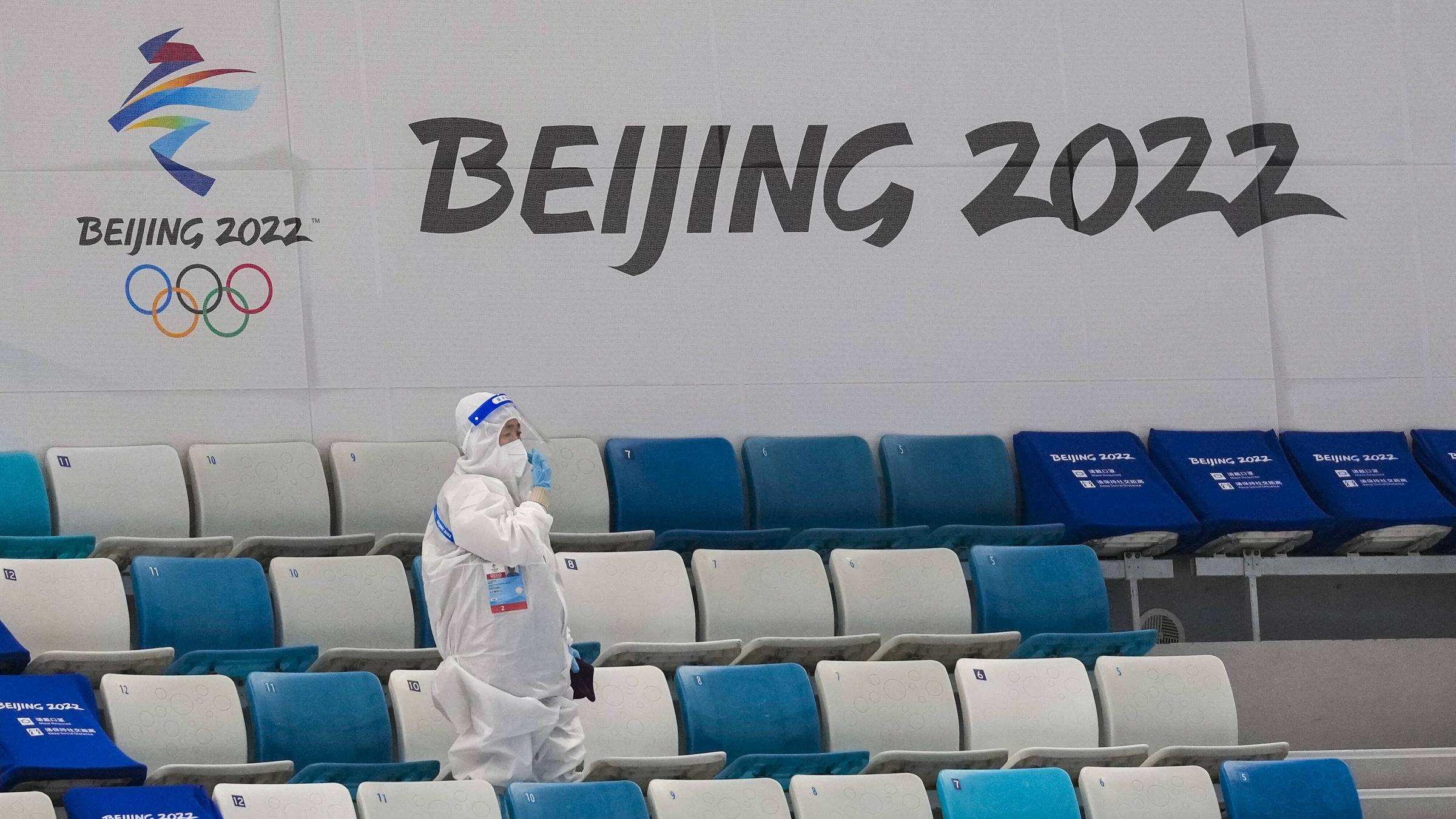 In einem leeren Stadion läuft eine Person mit weißen Ganzkörperanzug, als Schutz vor dem Virus.