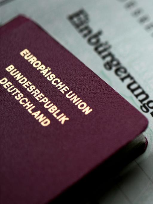 Ein deutscher Reisepass und eine Einbürgerungsurkunde liegen übereinander.