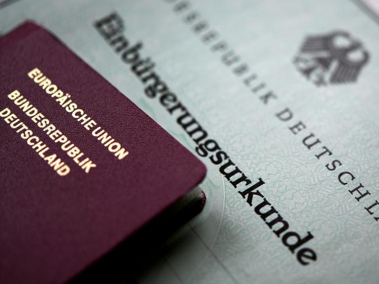 Ein deutscher Reisepass und eine Einbürgerungsurkunde liegen übereinander.