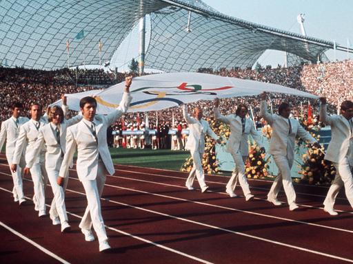 Die Mannschaft des deutschen Gold-Achters (Rudern) von Mexiko 1968 trägt die Olympische Fahne feierlich in das Münchener Olympiastadion während der Eröffnungsfeier der Olympischen Sommerspiele am 26. August 1972.