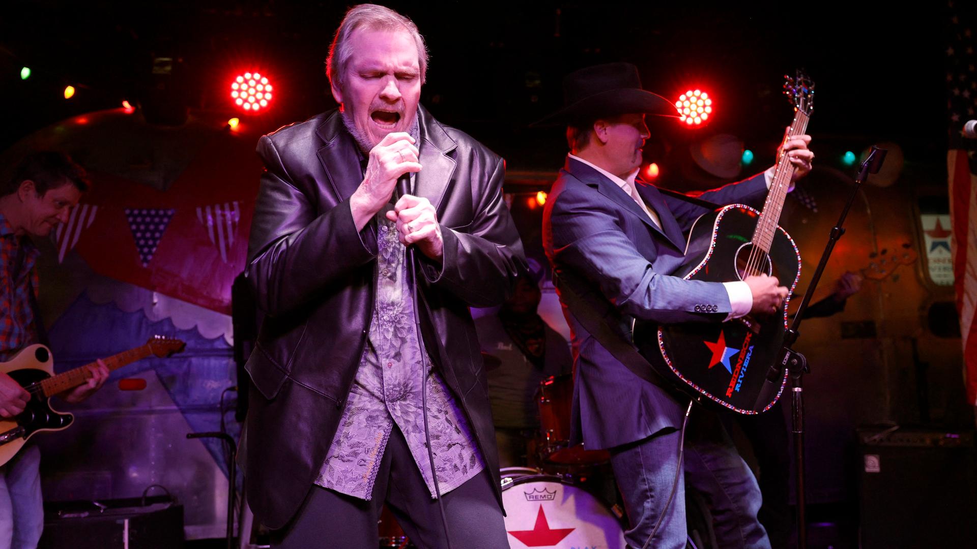 Der US-Rock-Sänger Meat Loaf trägt ein gemustertes Hemd und eine Leder-Jacke. Er steht auf einer Bühne und singt in ein Mikrofon. Der US-Rock-Sänger Meat Loaf trägt ein gemustertes Hemd und eine Leder-Jacke. Er steht auf einer Bühne und singt in ein Mikrofon.