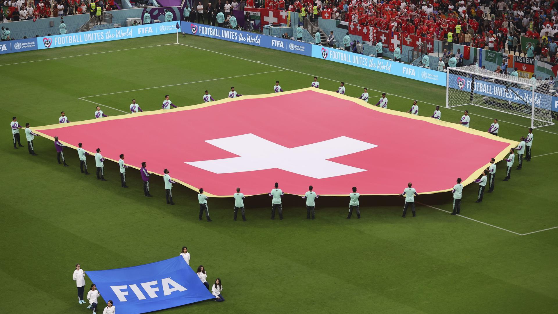 Die Schweizer Flagge wird vor dem WM-Achtelfinale in Doha auf den Rasen in Lusail City getragen. Die Schweizer Flagge wird vor dem WM-Achtelfinale in Doha auf den Rasen in Lusail City getragen.