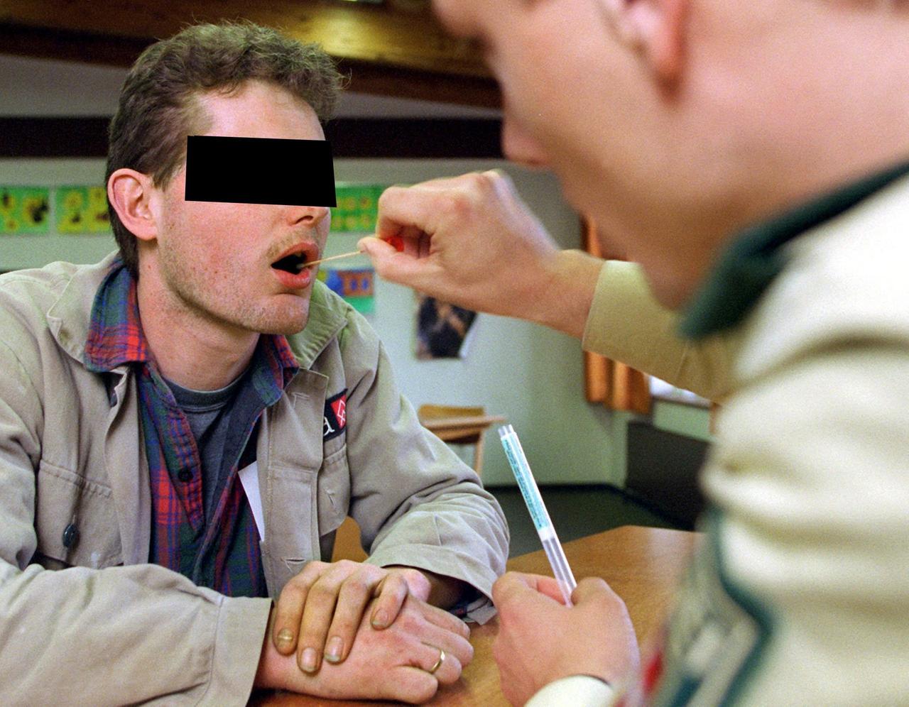 Ein Polizeibeamter entnimmt einem jungen Mann im April 1998 mit einem Wattestäbchen Speichel aus dem Mund (Archivbild). 