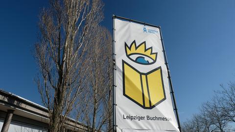 Ein Banner mit der Aufschrift "Leipziger Buchmesse" und einem gemalten Buch unter einer gemalten Krone flattert im Wind.