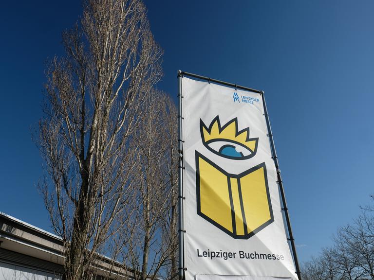 Ein Banner mit der Aufschrift "Leipziger Buchmesse" und einem gemalten Buch unter einer gemalten Krone flattert im Wind.