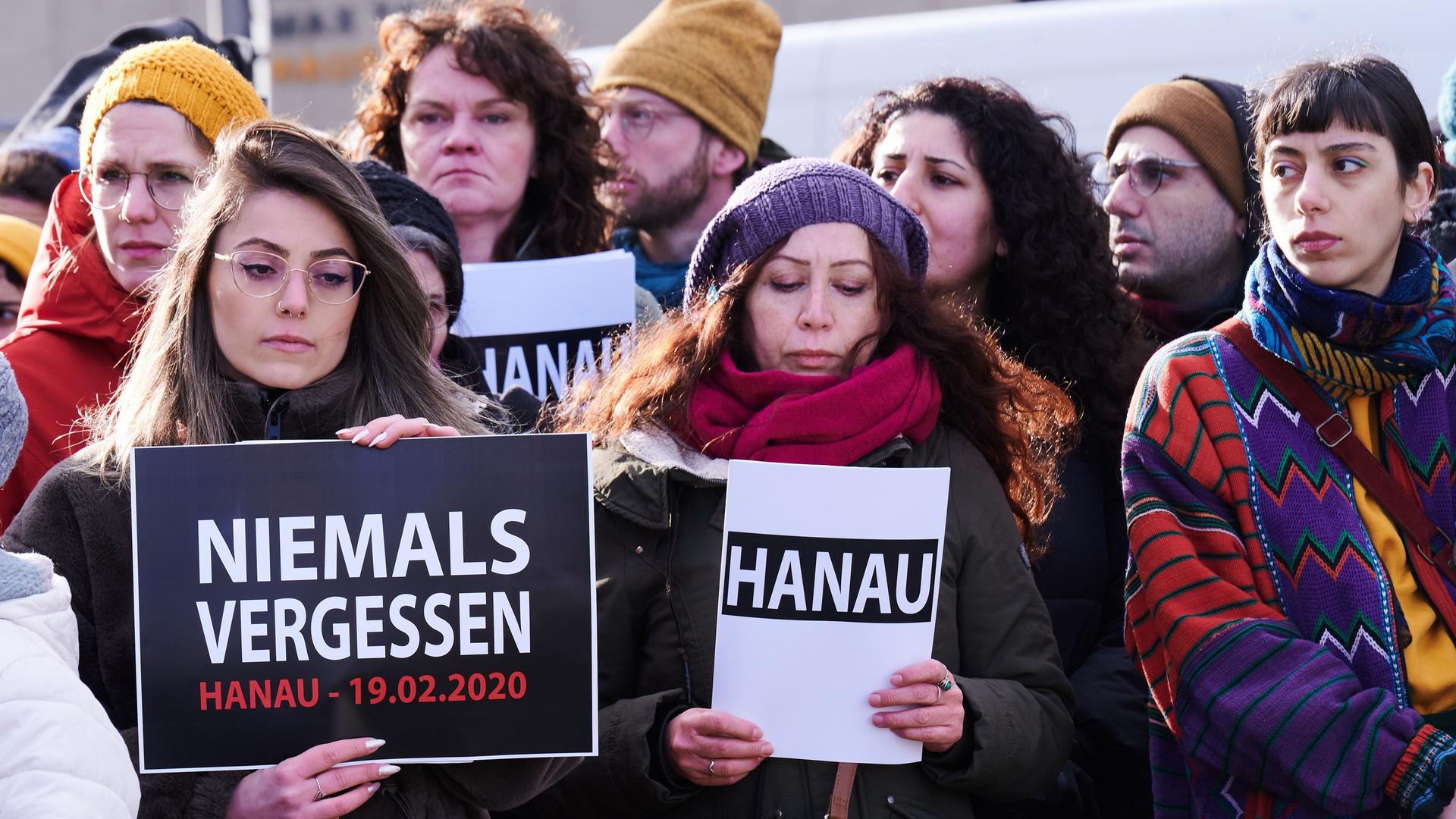 "Hanau" und "Niemals vergessen" steht auf den Schildern, die ein Chor bei der Gedenkveranstaltung eines Bündnisses von Initiativen und Organisationen auf dem Oranienplatz hält. Ein 43-jähriger Deutscher hatte am 19. Februar 2020 in Hanau neun Menschen aus rassistischen Motiven ermordet. "Hanau" und "Niemals vergessen" steht auf den Schildern, die ein Chor bei der Gedenkveranstaltung eines Bündnisses von Initiativen und Organisationen auf dem Oranienplatz hält. Ein 43-jähriger Deutscher hatte am 19. Februar 2020 in Hanau neun Menschen aus rassistischen Motiven ermordet.