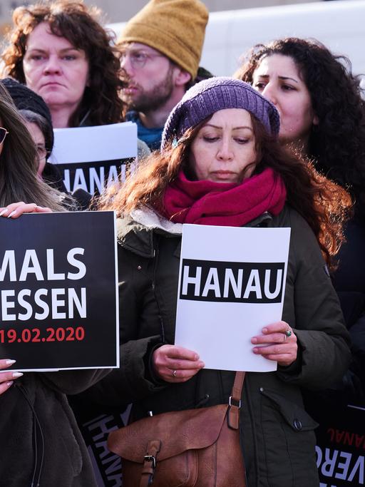 "Hanau" und "Niemals vergessen" steht auf den Schildern, die ein Chor bei der Gedenkveranstaltung eines Bündnisses von Initiativen und Organisationen auf dem Oranienplatz hält. Ein 43-jähriger Deutscher hatte am 19. Februar 2020 in Hanau neun Menschen aus rassistischen Motiven ermordet.
