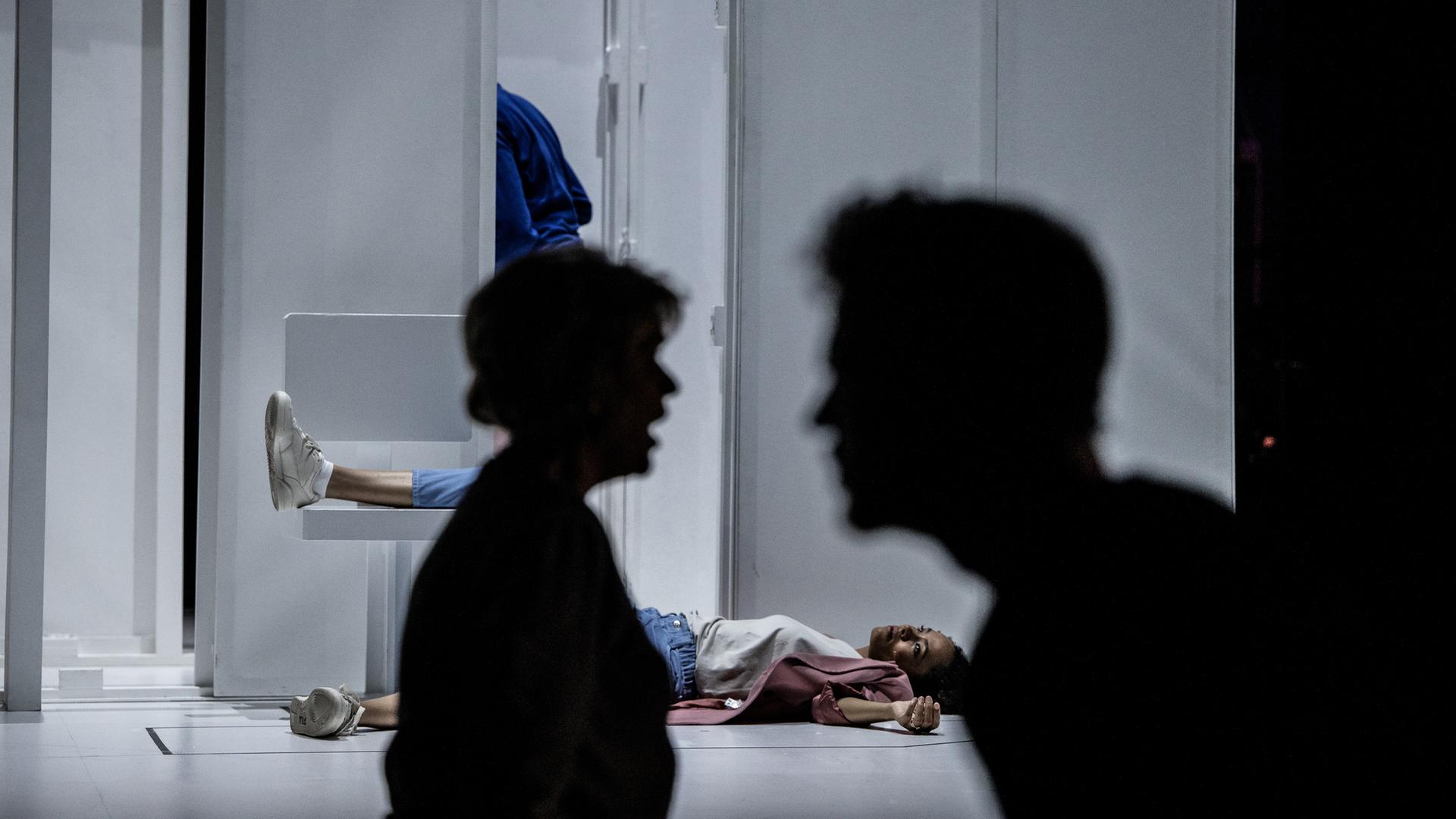 Schatten zweier Gesichter, dahinter liegt ein Mensch am Boden Schatten zweier Gesichter, dahinter liegt ein Mensch am Boden