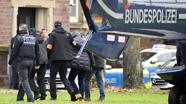 Baden-Württemberg, Karlsruhe: Eine Person (2.v.r.) wird von Polizisten aus einem Hubschrauber gebracht.