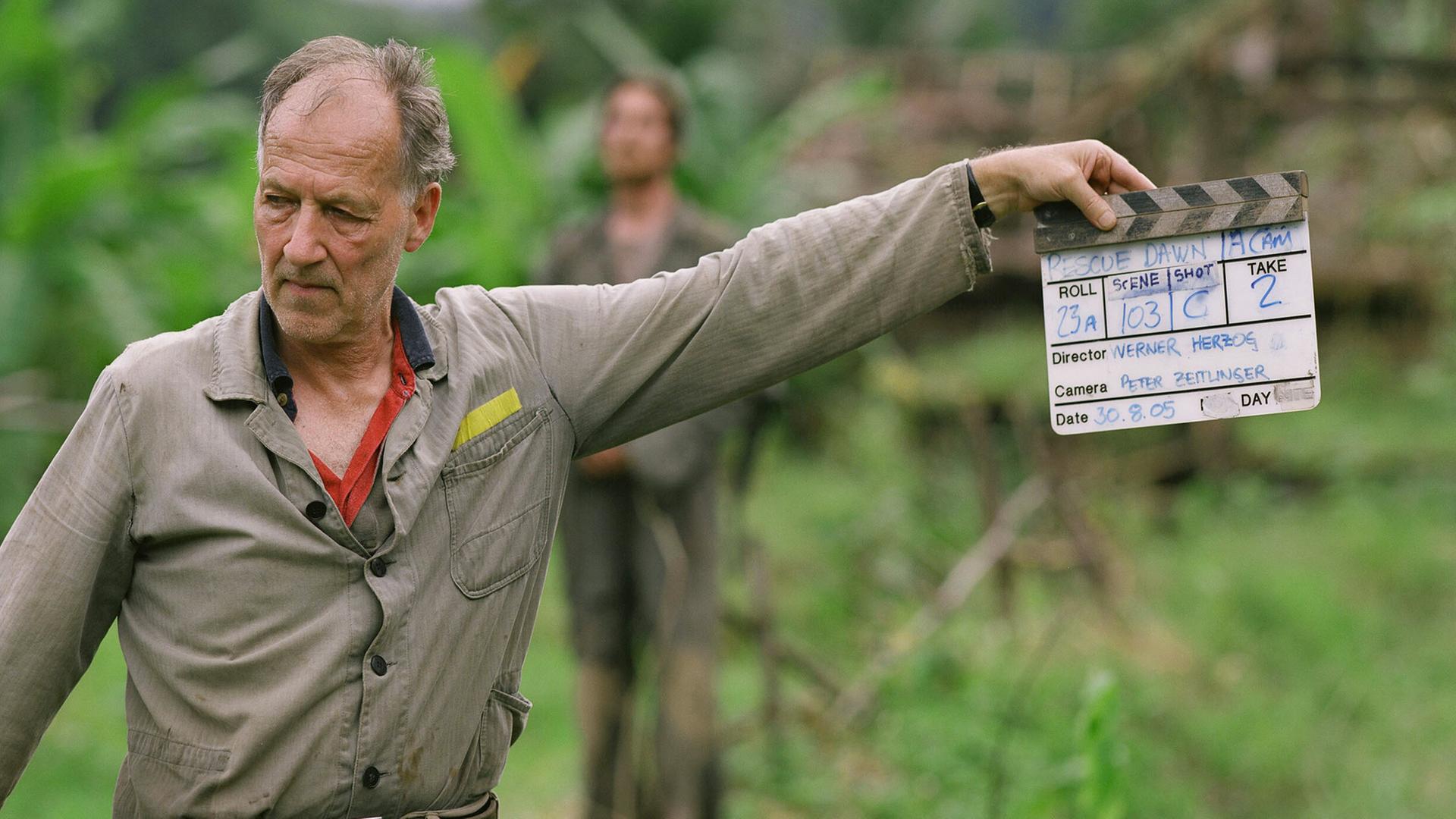 Ein von den Dreharbeiten im Dschungel sichtlich mitgenommener Werner Herzog schlägt die Klappe vor der Kamera Ein von den Dreharbeiten im Dschungel sichtlich mitgenommener Werner Herzog schlägt die Klappe vor der Kamera