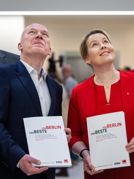 Die Berliner Politiker Kai Wegner, Vorsitzender der CDU in Berlin, und Franziska Giffey, SPD und derzeit noch Regierende Bürgermeisterin von Berlin, präsentieren den Berliner Koalitonsvertrag. Sie lächeln und blicken nach oben.