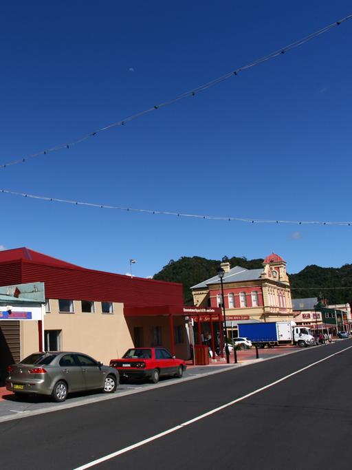 Eine Häuserfassde in der australischen Kleinstadt australische Queenstown, vor der Autos parken.