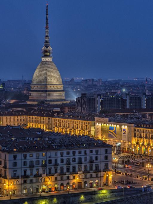 Die erleuchtete Stadt Turin bei Nacht, über der die Mole Antonelliana thront. Der pavillonartige Bau mit seinem hohen, sich stark verjüngenden Aufsatz ist das Wahrzeichen der Stadt.
