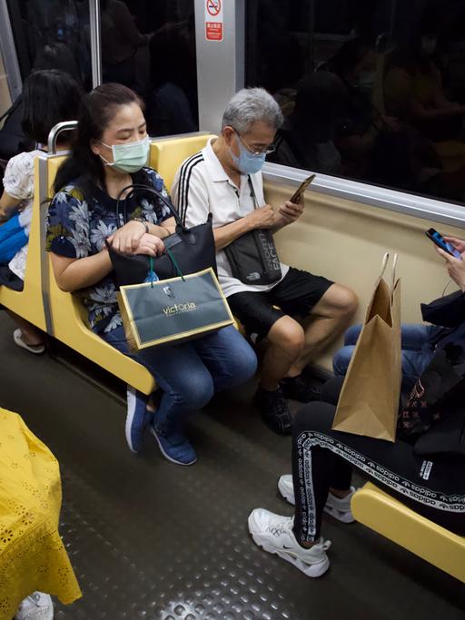 Fahrgäste in der U-Bahn von Taipeh. Die meisten tragen Masken und schauen auf ihre Smartphones.