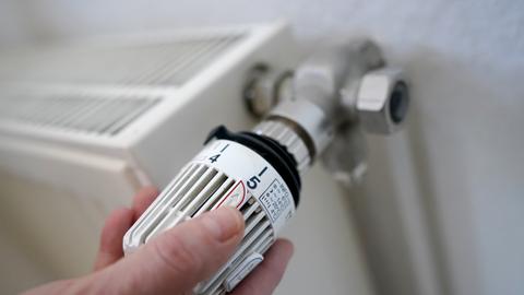 Eine Frau dreht an einem Heizungsthermostat. Die steigenden Energiekosten bereiten vielen Haushalten Sorge.