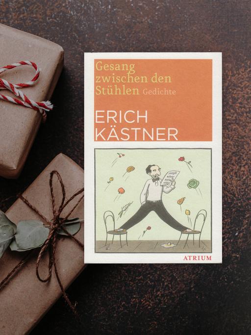 Buchcover von "Gesang zwischen den Stühlen" von Erich Kästner. Im Hintergrund sind braune Päckchen mit weiß-roten Schleifen zu sehen.