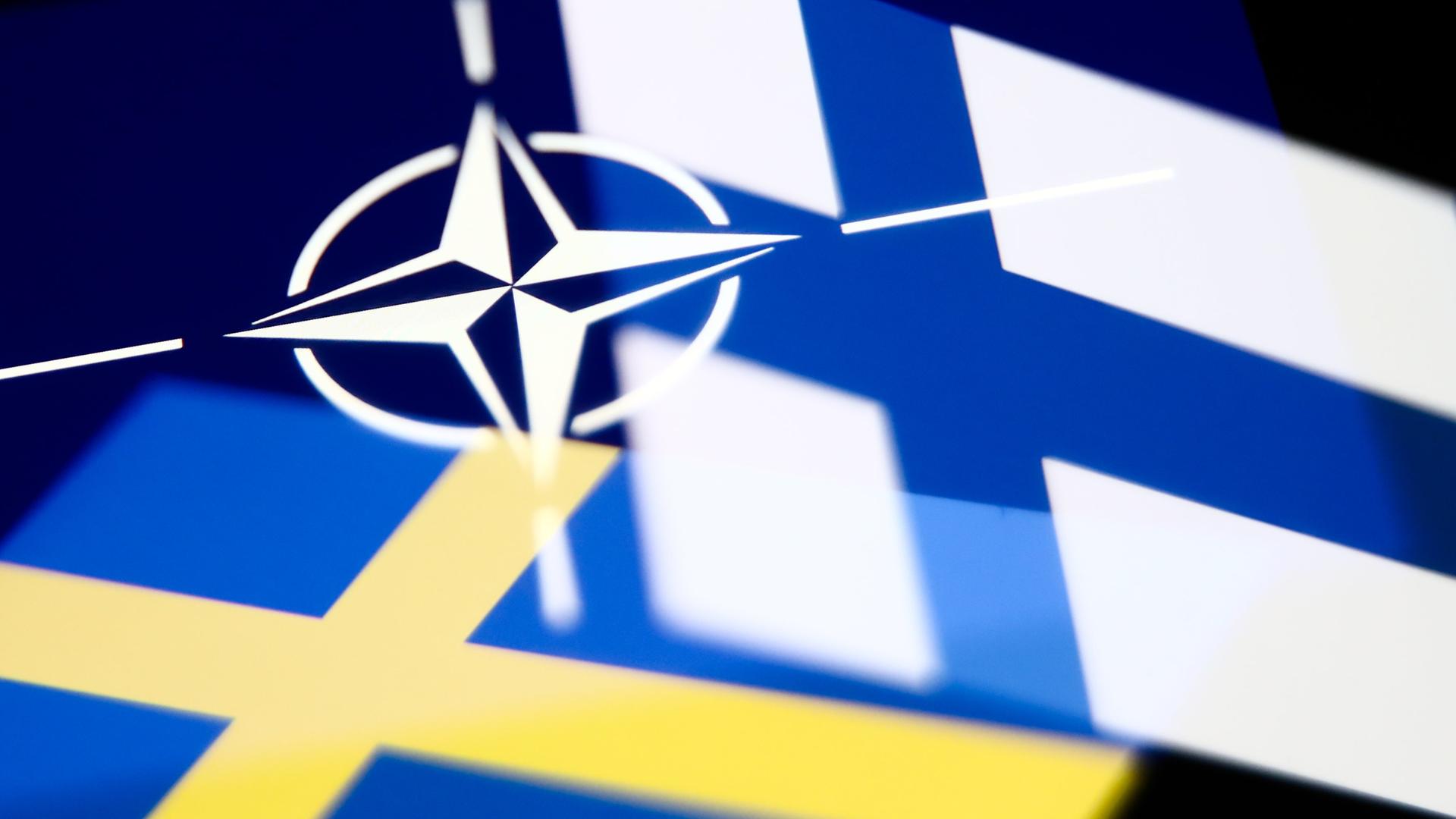 Die Flaggen von Schweden und Finnland sowie das Logo der NATO