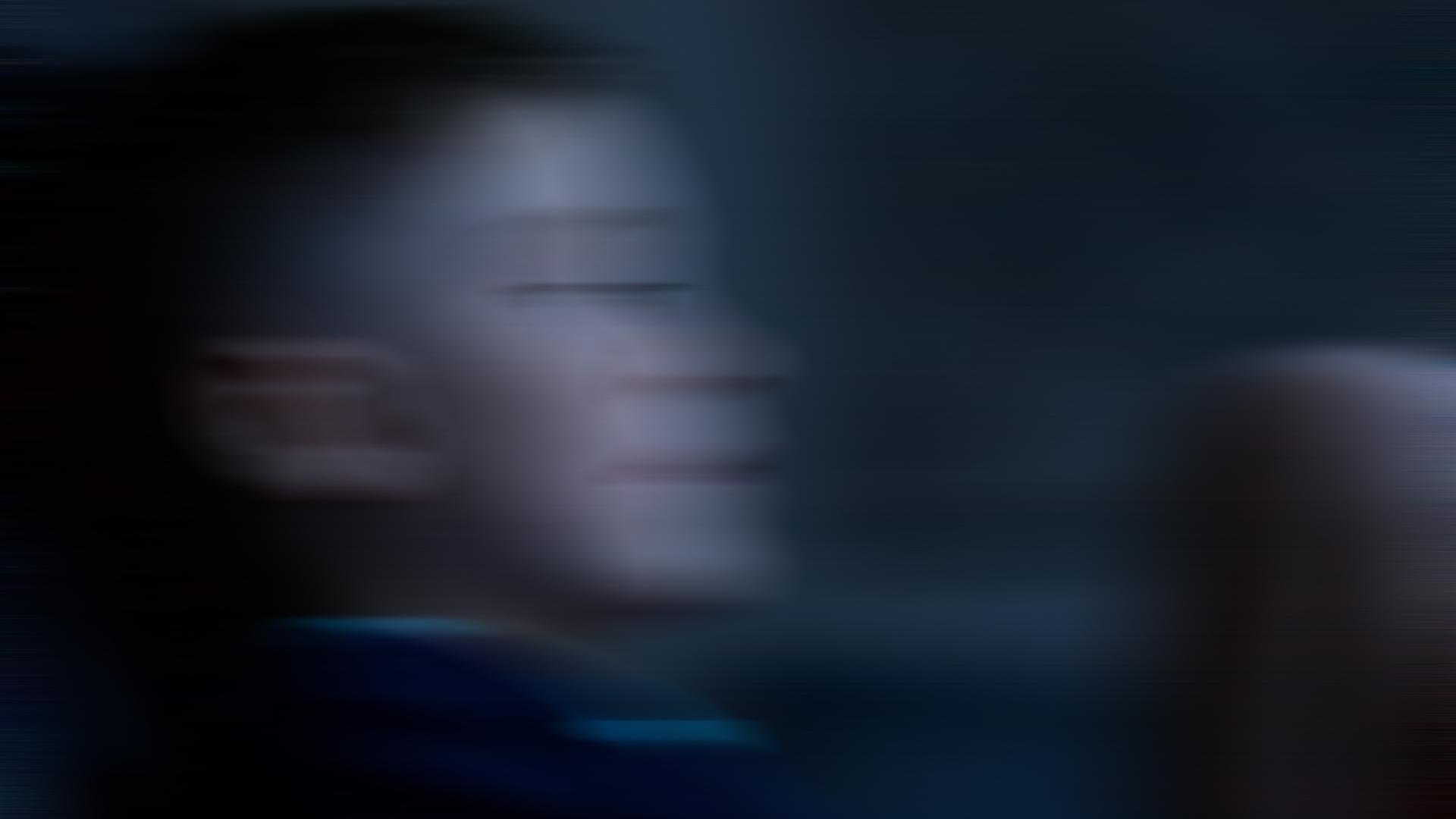 Ein Junge vor dunklem Hintergrund. Das Bild ist mit Bewegungsunschärfe verfremdet.