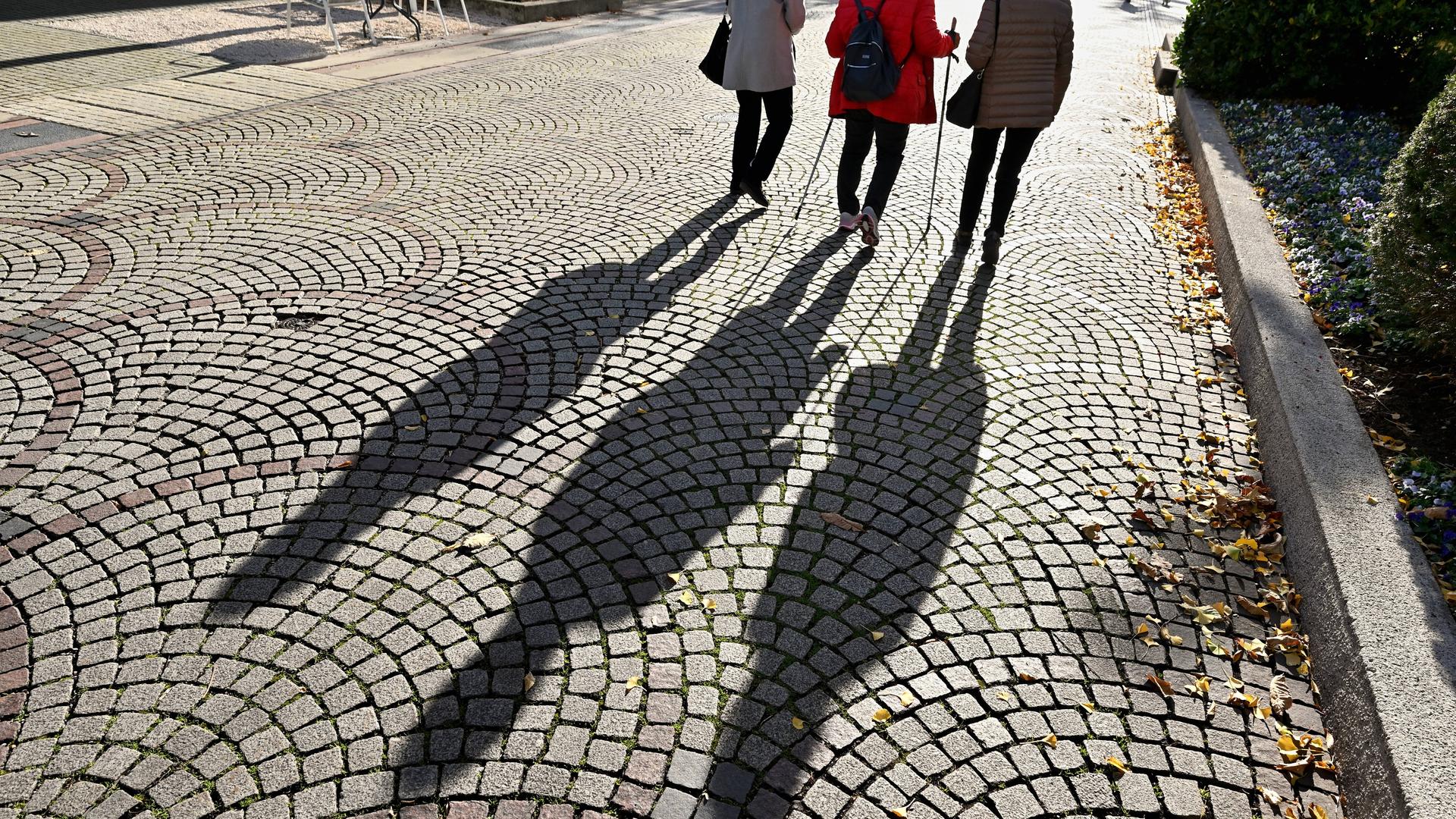Spaziergang im Herbst. Personen werfen einen malerischen Schatten auf das Kopfsteinpflaster in der Fußgängerzone von Bad Reichenhall. Spaziergang im Herbst. Personen werfen einen malerischen Schatten auf das Kopfsteinpflaster in der Fußgängerzone von Bad Reichenhall.