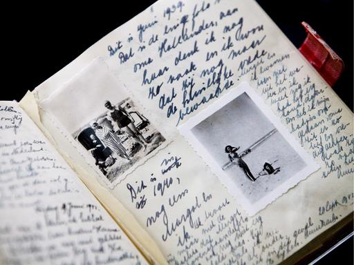 Großaufnahme eines handschriftlich gefüllten Notizbuches, in das Fotos eingeklebt wurden.