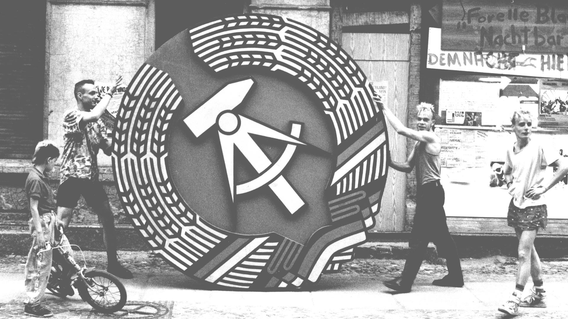 Zwei Männer halten ein Symbol der DDR Zwei Männer halten ein Symbol der DDR
