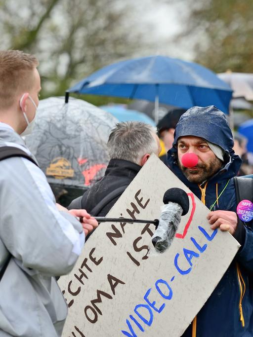 Im Bild, ein Teilnehmer einer Querdenken Demonstration in April 2021 mit Clownnase gibt Journalisten ein Interview.