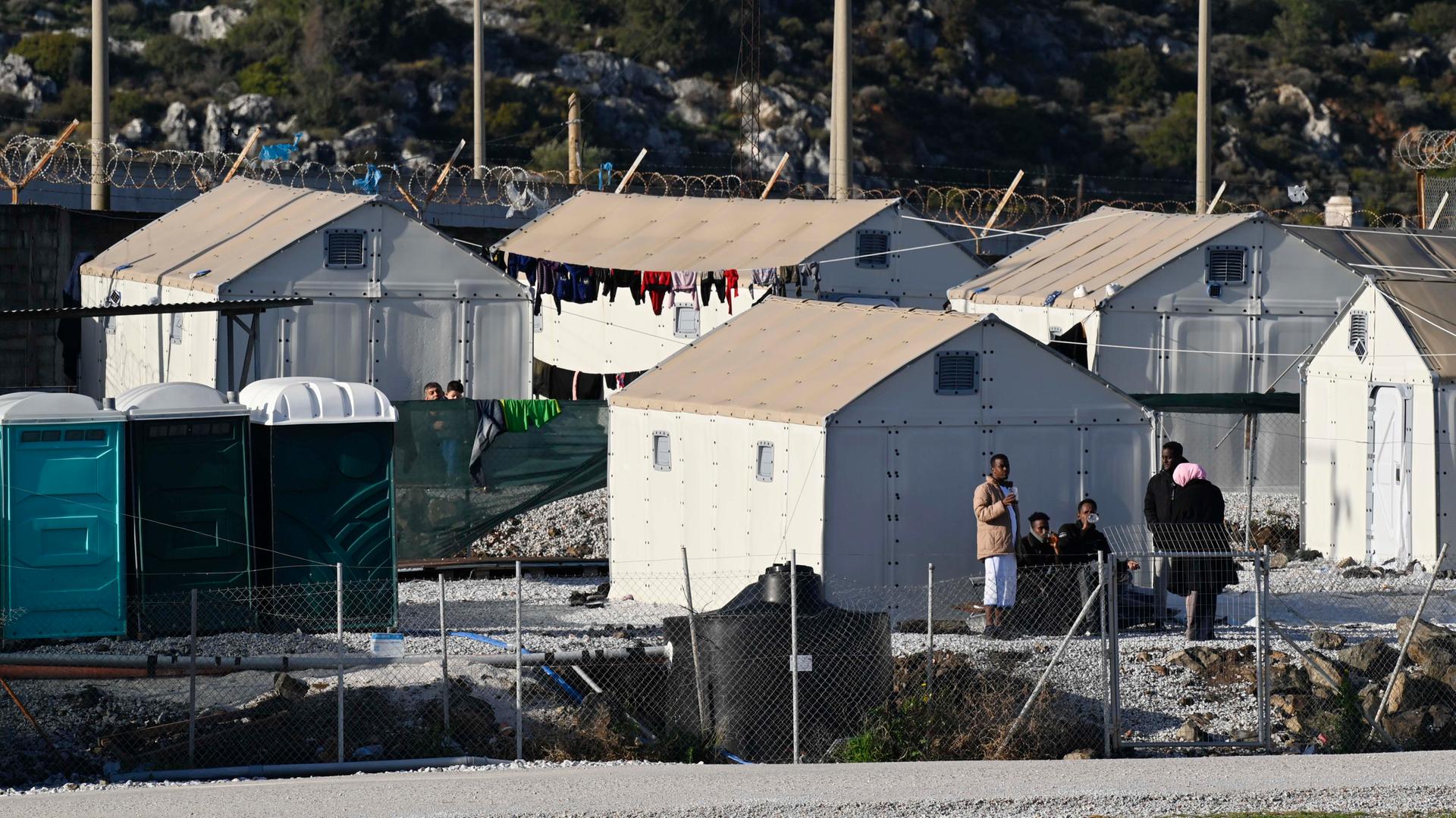 Mehrere provisorische Zelte stehen im Flüchtlingslager Moria auf der griechischen Insel Lesbos, vor einigen stehen Migranten. 