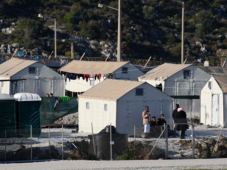 Mehrere provisorische Zelte stehen im Flüchtlingslager Moria auf der griechischen Insel Lesbos, vor einigen stehen Migranten. 