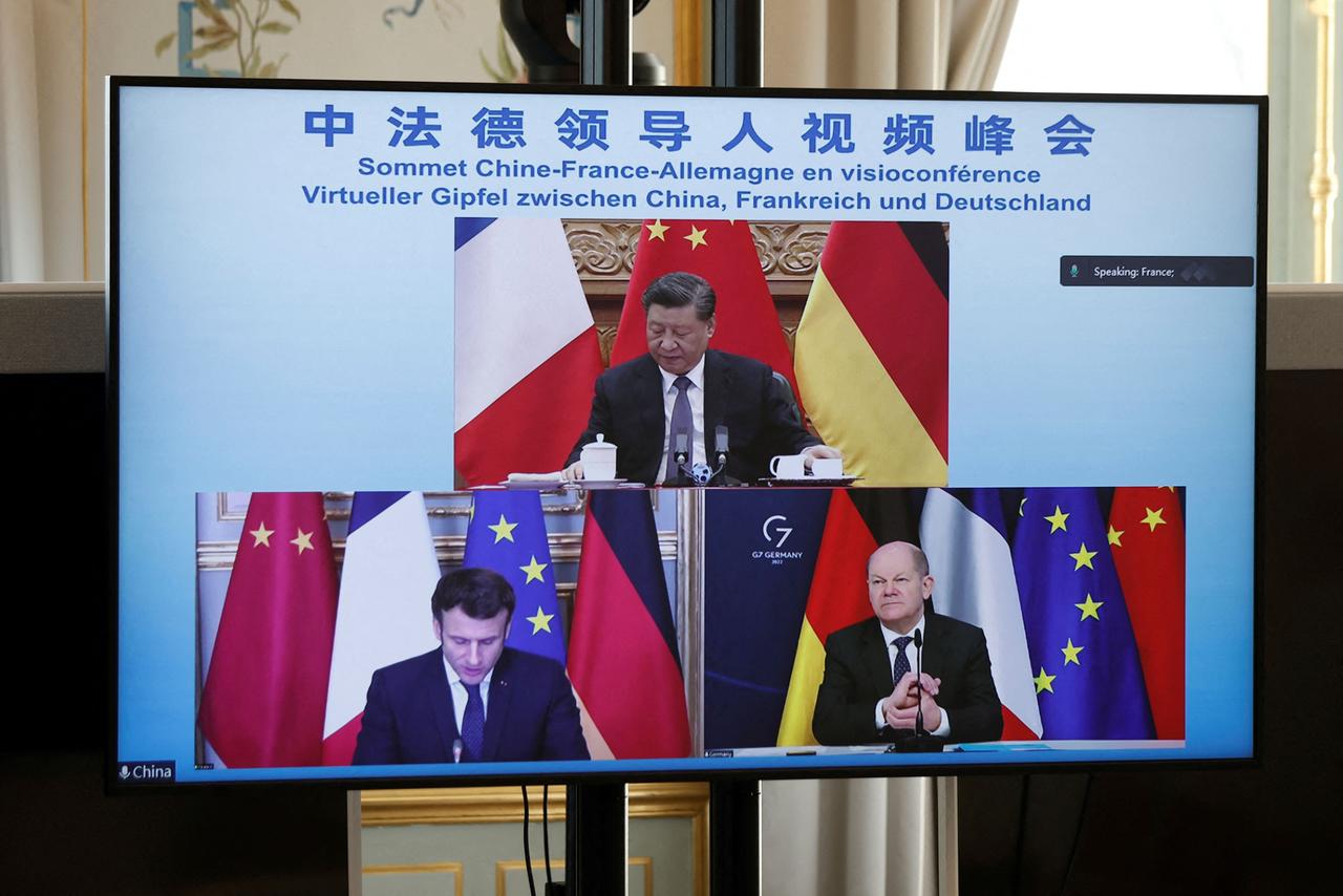 Ein Bildschirm, auf dem Bundeskanzler Scholz, Frankreichs Präsident Macron und Chinas Präsident Xi Jinping in einer Videkonferenz zu sehen sind.