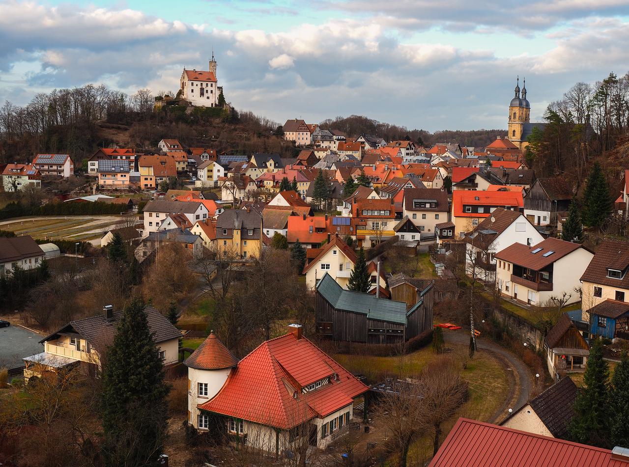 Ansicht des Markts Gößweinstein mit Kirchtürmen und einer kleinen Burg auf einem Hügel. Ansicht des Markts Gößweinstein mit Kirchtürmen und einer kleinen Burg auf einem Hügel.