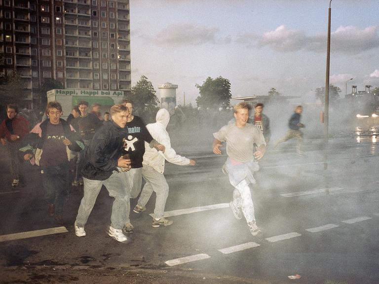 Demonstrierende rechtsextreme Jugendliche in Rostock im Strahl von Wasserwerfern der Polizei, Spätersommer 1992.