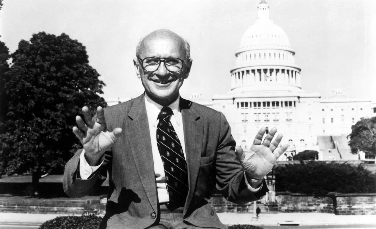 Milton Friedman steht vorm Capitol in Washington und lächelt freundlich in die Kamera. (Schwarzweiß Aufnahme)