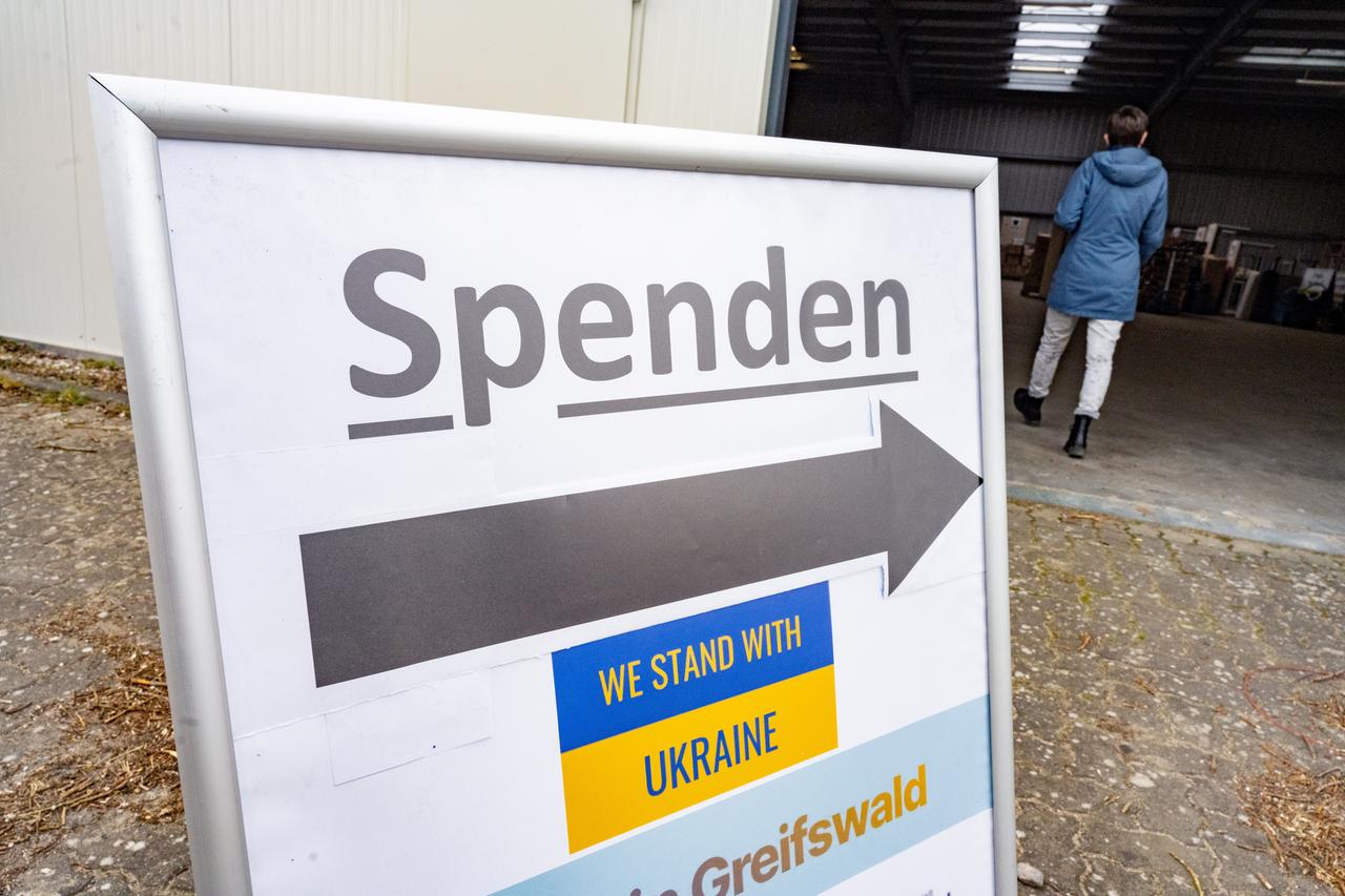 Ein Schild "Spenden, we stand with Ukraine" steht vor einer Sammelhalle in Greifswald.