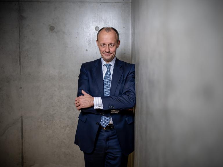 Der CDU-Politiker Friedrich Merz steht im Jakob-Kaiser-Haus des Deutschen Bundestags vor einer grauen Betonwand und verschränkt die Arme.