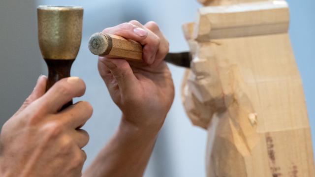 Ein Bildhauer arbeitet an einem Kunstwerk aus Holz